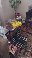Photo showing a variety of boxed board games including Yahtzee, a yellow boxed game, and a backgammon set on a small table near a plant.