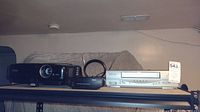 Shelf setup showing Epson projector, Emerson VHS player, RCA video selector, and TV antenna