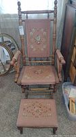 Full view of vintage wooden platform rocker chair and matching needlepoint footstool.