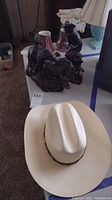 Photo showing one of the plaster western sculptures alongside the cowboy hat on a table.