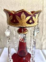 Close-up of top edge showing painted gold leaf pattern and hanging crystal prisms.