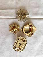 Back view showing the pin and clasp mechanisms of the five gold-tone vintage brooches.