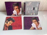 Collectible Elvis Presley CD albums with cover art and booklets in jewel and cardboard cases arranged on a table.