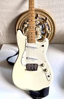 Front view of guitar body and included strap laid on surface