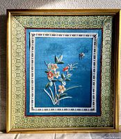 Front view of the framed silk painting with floral design on turquoise silk, showing the detailed borders and gold frame.