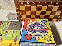 Wood chess board, Cranium game box, and two sealed card packs arranged on a table.