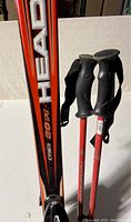 Pair of Head skis standing upright with Rossignol poles leaning
