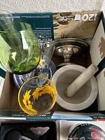 Box containing mortar and pestle, various glasses with floral and etched designs, and metal dish.