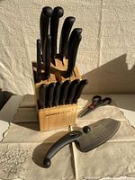 Full view of Miracle Blade cutlery set in wooden block on cloth surface with Rock n Chop knife and scissors displayed in front.