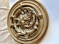 Close-up image showing the ornate oak leaf design and gold finish of the mirror frame.