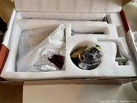 View of faucet components still in protective foam packaging inside original box.