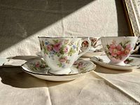 Close-up of two Royal Albert teacup sets with pink rose and blue floral patterns highlighting the gold trim and delicate china.