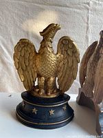 Close-up of one copper cast eagle bookend on a black base with gold stars.