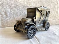 Front three-quarters view of the vintage Stanley metal car coin bank on a plain cloth background used to show the shape, detailing, and condition of the item.