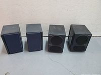 Front view of two pairs of small speakers, two Sony pairs with front grilles on, and two JVC speakers with grilles off showing drivers