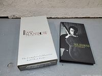 Barry Manilow box set with white outer box and Neil Diamond box set with black cover featuring the artist.