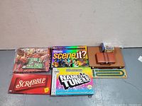 Overview of all games including Scrabble, Scene It?, Name That Tune, Othello, a cribbage board, dominos and card decks on floor