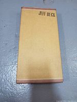 Front cover of Jeff Beck Beckology box set showing textured golden-yellow suitcase style design with brown corner accents and 'JEFF BECK' text.