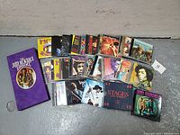 Photo showing 22 CDs with colorful covers and purple Jimi Hendrix Experience box set, laid out on concrete floor.