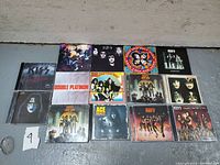 Top-down photo showing 15 Kiss music CDs laid out in rows with album art visible