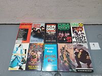 Photo showing front covers of nine vintage rap VHS tapes featuring iconic hip-hop artists and groups such as Run DMC, Public Enemy, Salt-N-Pepa, and others.