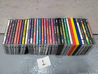 25 dance music CDs lined up side by side, showing colorful spines with various titles related to 90s dance and club music.