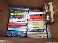 Photo showing a box full of assorted music VHS tapes with visible titles and artists.