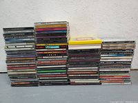Photo showing multiple stacks of 90s CDs in jewel cases, mostly spine labels visible.