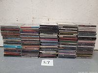 Wide view of stacked CDs, showing the variety and quantity of albums included in the lot.