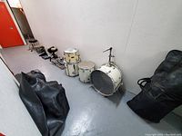 Wide shot of drum shells and pedals showing white Pearl drums of maple and birch shells, particle drum, bass drum, floor toms and pedals arranged on floor