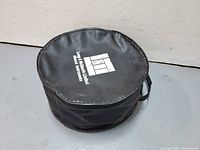 Soft black padded carrying case for snare drum, showing top with handle and logo