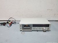 Front view of the Technics M225 cassette deck showing silver finish and cassette compartment with cassette inserted, control buttons and input/output knobs visible.