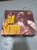Front view of the Verve Jazz Singing CD box set, showing a black and white photo of a jazz singer with yellow text.