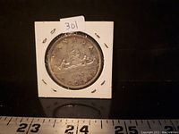 Front side of 1962 Canadian silver dollar coin showing the canoe design, two paddlers, and trees from Canada.