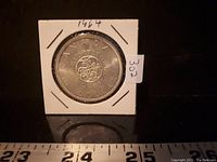 Reverse view of 1964 Canadian silver dollar coin showing floral design and inscriptions.