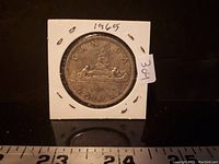 Photo of reverse side of 1965 Canadian silver dollar showing Bluenose schooner design and inscriptions.