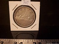 Front side of the 1965 Canadian Silver Dollar showing the canoe design, year 1965, and denomination.