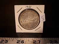 Reverse side of 1966 Canadian silver dollar coin showing Voyageur design, date 1966, and denomination 'DOLLAR'.