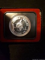 Close-up of 1975 Canadian Silver Dollar proof coin featuring mounted rider design with inscriptions 'CANADA DOLLAR', 'CALGARY 1975', 'DPP' in protective capsule and red lining.