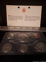 Photo of the seven uncirculated Canadian coins sealed in plastic with an informational card behind them.