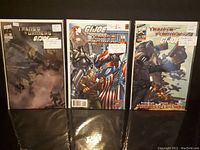 Three Transformers G.I. Joe comics arranged side by side on black surface.
