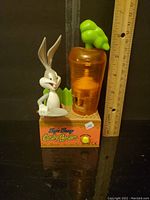 Front view of Bugs Bunny candy holder with carrot-shaped candy dispenser and ruler for size comparison.