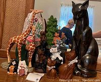 Wide view showing large giraffe figurines, clustered dog figurines, green frog figurines, and multiple cat figurines including tall black glossy cat.