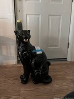 Full side view of the black ceramic panther statue showing glossy finish and details.