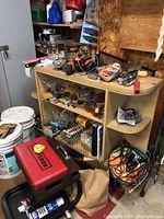 Photo showing red Craftsman kneeling cart, wooden shelf with tools and hardware on and around it.