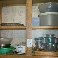 Shelf with various kitchen items including Corning Ware dishes, plastic bowls, and green glass baking dish