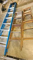 Three ladders laid out flat showing the full length and condition with paint splatters.