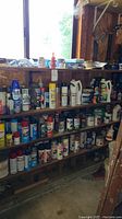 Long view of shelves with various spray cans and chemical bottles, mostly spray paint cans in multiple colors.