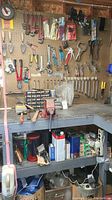 Full view of pegboard with bench vise, assorted wrenches, pliers and tools hung above workbench