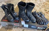 Pair of black Your Aster motorcycle boots with molded shin protectors and reinforced toes, size US 10.5, next to padded leather gloves on store box